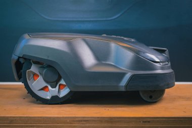 Robotik çim biçme makinesinin temiz yan görüntüsü, bir yıl çamurda ve çimlerde kullanıldıktan sonra motorlu çim biçme makinesinin bir masada servise verilmesi. Robot çim biçme makinesinin düzenli bakımı