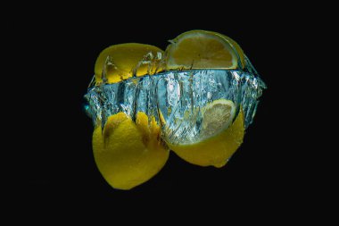 Taze limonun yarısı suya düşer büyük damlalar saçar ve koyu bir arka plana püskürtür. Güzel bir su tacı yapmak için sulu ve taze limon konsepti.