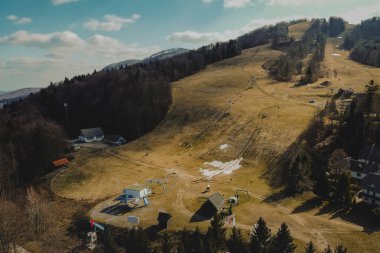 Kurak kış döneminde küçük bir kayak merkezinin havadan çekilmiş fotoğrafı. Kar yağmayan kötü ve kuru hava nedeniyle gelir kaybı, günümüz kayak merkezlerinin sorunları, Slovenya 'nın Gace kentindeki gibi