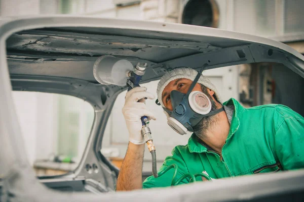 作为一项修复工程 白人男子正在古董车上喷涂带有压缩空气油漆枪的颜色 戴面具和手套等防护设备的人 专业汽车漆工 — 图库照片