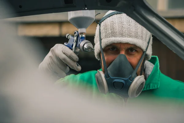 白人男性は修復プロジェクトとしてヴィンテージカーに圧縮空気塗料銃で色を噴霧しています マスクや手袋などの保護具を身に着けている男 プロの自動車画家 — ストック写真
