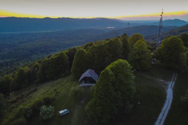 Slovenya 'nın Kocevsko bölgesinde gün batımında veya akşam saatlerinde bir minibüsle vahşi bir kamp. Dağ kulübesi ve antenleriyle Kocevje 'nin etrafındaki tepelerin güzel manzarası..