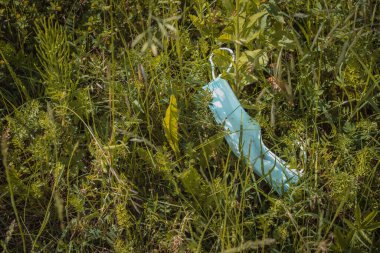 Korunmasız yüz maskesi doğada. Hava kirliliği ve güvenlik maskesi. Doğadaki çöp artışı ve trendi - koruyucu maskeler.