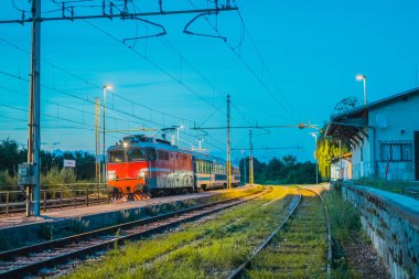Slovenya 'daki Preserje istasyonunda geceleri klasik yolcu vagonları taşıyan yolcu treni. Daha eski bir trenin akşam ayarı.