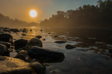 Sabahın erken saatlerinde nehir ve nehir taşlarıyla puslu bir manzara. Sabahın erken saatlerinde mistik bir ortam.
