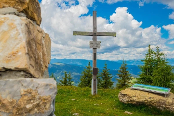 Wooden religious cross on the top of a hill in Austria. Grebenzen Dreiwald kogel close to Sankt Lambrecht ion a sunny and cloudy weather.