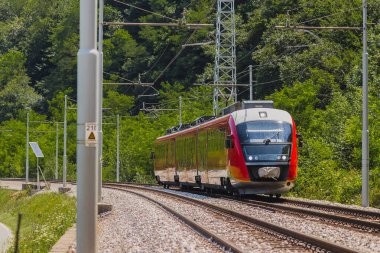 Modern elektrikli çoklu tren açık yolda. Güneşli bir günde kırsal kesimde şehre doğru koşan banliyö treni..