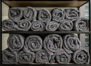 Çekmecede yığılmış bir sürü gri banyo havlusu. Banyoda bir sürü gri rulo havluyla dolu raflar var. Tuvaletteki spa hissi.