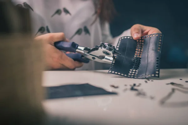 Woman is seen using a punch tool or hole maker. Craft or crafty woman using a hole tool to make holes in rubber material.