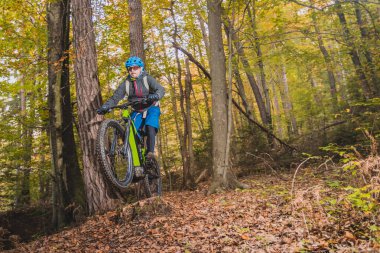 Sonbaharda ya da kış aylarında ormanda modern bir elektrikli bisiklet ya da dağ bisikletiyle yokuş aşağı giden bir bisikletçi. Ormanda modern bir bisikletçi..