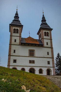 Slovenya 'da Skofja Loka yakınlarında Poljanska vadisindeki Saint Volbenk kilisesinin soğuk sonbahar panoraması.