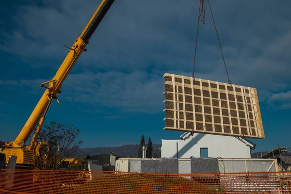 Building a prefabricated wooden house - raising or hoisting house section with a help of a crane.