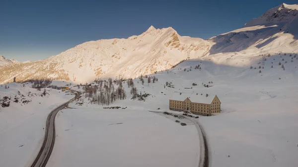 冬の雪に覆われたシンプソン峠の頂上にあるシンプソン ホスピスの空中ドローン写真 太陽の下での入浴の背景に見える山々と雪の大規模な量で囲まれた家 — ストック写真