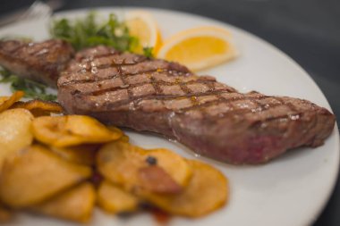 Biber ya da hardal bifteği, bir tabakta ızgara ve bir restoranda fırında patates ile servis edilir. Beyaz tabakta servis edilen lezzetli yemek..