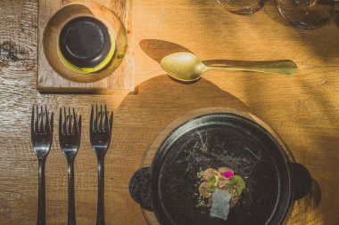 Süslü gümüşler, çanak çömlek, tabak ve diğer şeyler bir masanın üstünde, yukarıdan bakan süslü bir yemek türü ile.