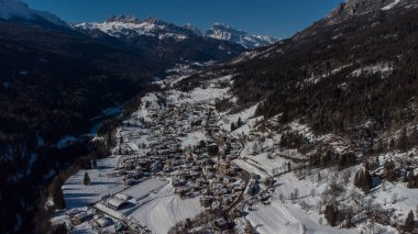 Cortina d 'Ampezzo etrafındaki vadinin hava aracı görüntüsü, güneşli bir günde Volo di Cadore köyünden karlı tepelere doğru bakıyor..