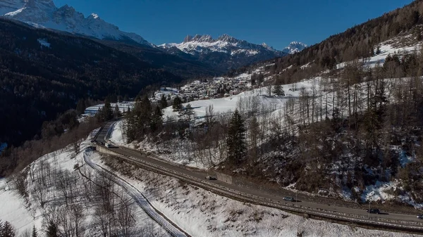 コルティナ ダンペッツォ周辺の谷の空中ドローンの景色 晴れた日に2月に雪の丘に向かってVolo Cadoreの村から見て — ストック写真