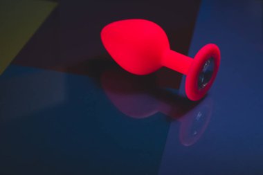 Beautiful smooth pink butt plug or buttplug, sex toy, on a colorful background. Contrast photo of an anal toy on a cool background.