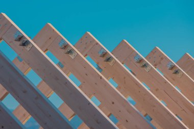 Modern ahşap çatı çerçeve veya çerçeveler, yenilenmiş bir evin kirişleri ile iskelet. Arka planda mavi gökyüzü