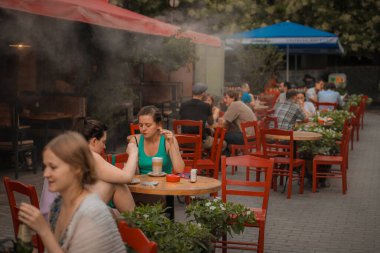 TBILISI, GEORGIA, 20.7.2012: İnsanlar covid veya corona zamanlarından önce bir barda maskesiz güzel kırmızı sandalyelerde oturarak içki içmekten zevk alıyorlar.