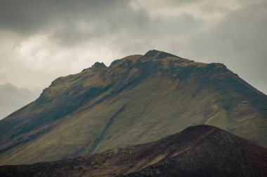 Hava manzaralı yol, bulutlu bir yaz gününde Snfellsnesvegur, Islandija yakınlarındaki Lav kayaları oluşumlarından geçiyor. Muhteşem lav sahası ve yol delip geçiyor..