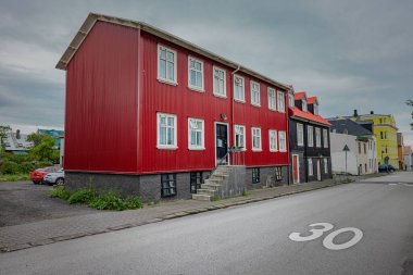 Reykjavik veya diğer köylerdeki çoğu İzlanda evlerinde kırmızı cepheli tipik bir ev. Aşağıdan yol ve diğer evlerle görünüm..