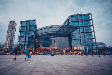 Berlin 'in akşam manzarası ya da ana tren istasyonu. İnsanlar oturmuş istasyona doğru yürüyorlar..
