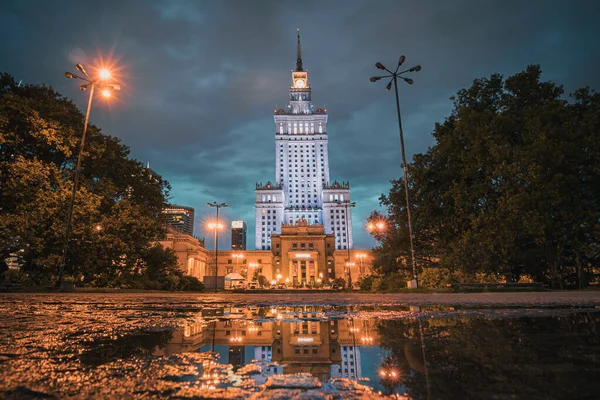 ポーランドのワルシャワにある芸術と文化の宮殿は 水溜りの中に見える建物を反映して 曇り空と雨の夜にあります 洗練された歴史的景観の美しい肖像画 — ストック写真