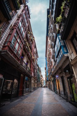 Bilbaos Casco Viejo 'da dar bir sokağa çarpan dramatik bir alçak açı demir balkonlu ve cam pencereli uzun, zengin binaları bulutlu bir gökyüzünün altında bir araya getirdi..