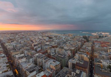 Bari alacakaranlıkta, tarihi merkezin panoramik manzarası, hareketli liman ve dramatik bulutlar ve yumuşak günbatımı altında Adriyatik Denizi.