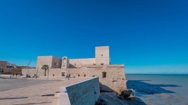 Geniş açı, Adriyatik kıyısında doğrudan inşa edilen 13. yüzyıldan kalma bir kale olan Trani 'deki görkemli Castello Svevo Swabian Kalesi' ni ele geçiriyor. Devasa kireçtaşı duvarları derin mavi deniz ve gökyüzüne karşı parıldıyor..