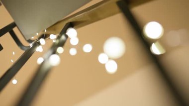 İnce gümüş bir tel üzerinde, koyu dikey sütunlara sarılı narin, ılık, beyaz peri ışıkları parıldıyor. Sığ alan derinliği tatil dekoru için rüya gibi, bokeh dolu bir atmosfer yaratıyor..