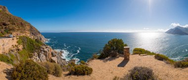 Hout Bay ve Sentinel Dağı 'nın panoramik ikonik manzarası manzaralı Chapmans Tepesi Yolu' ndan görülmektedir. Derin turkuaz Atlantik suları engebeli, kayalık bir kıyı şeridiyle buluşur..