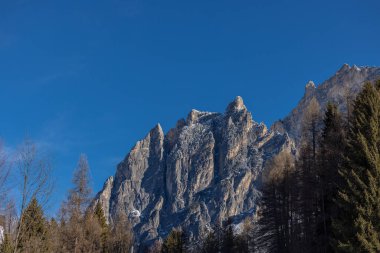 Sivri uçlu, dikey kireçtaşı zirveleri Cortina d Ampezzo 'nun kuzeyindeki derin mavi gökyüzüne karşı keskin bir şekilde yükselir, yoğun bir tarla kuşu ve daima yeşil kozalaklı ormanlarla çevrelenir..