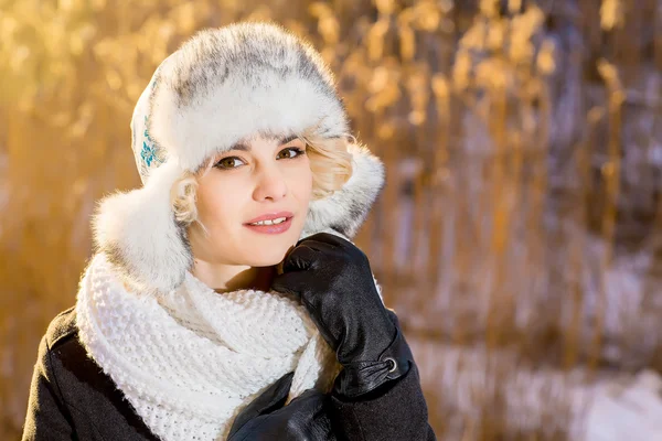 Blonde girl in a fur hat adjusts her scarf Royalty Free Stock Photos