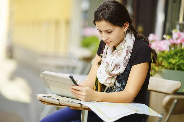 Молодая девушка сидит в кафе и смотрит на планшетный компьютер — стоковое фото
