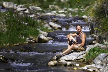 Gezgin fotoapparata bir dağ nehir kıyısında