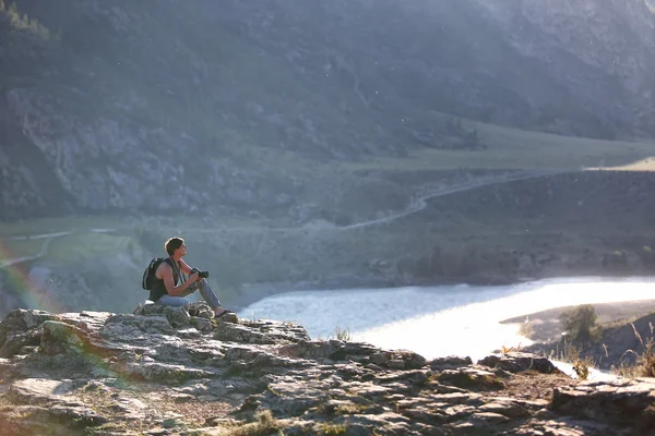 Young Man With A Backpack Sitting On The Edge Of Cliff Young Man With A Backpack Sitting On The Edge Of Cliff