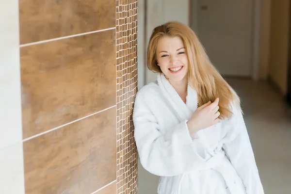 Blonde girl in a white robe laughs — Stock Photo, Image