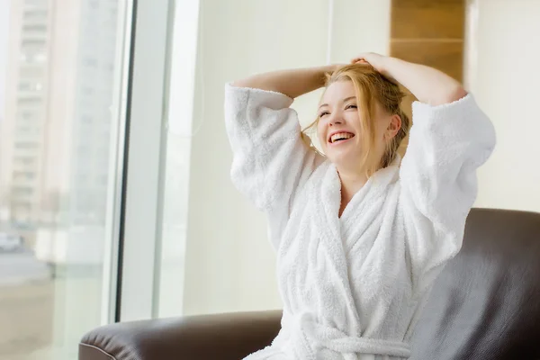 Beautiful blonde girl in a white robe laughs — Stock Photo, Image