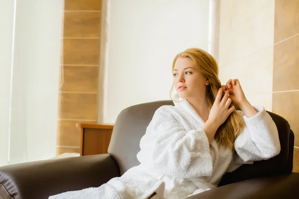 Beautiful young blonde girl in a white robe caresses — Stock Photo, Image