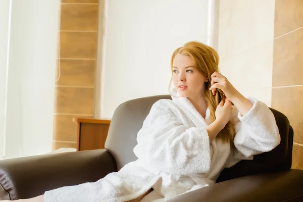 Beautiful young girl in a white robe combing hair — Stock Photo, Image