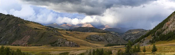 Beautiful plain on the backdrop of steep mountains in the rays Stock Picture