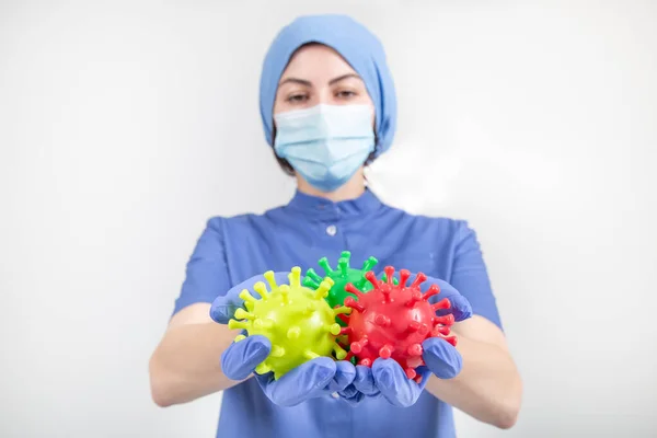 Coronavirüs oyuncakları taşıyan kırmızı, sarı ve yeşil üniformalı hemşire ya da doktor. 
