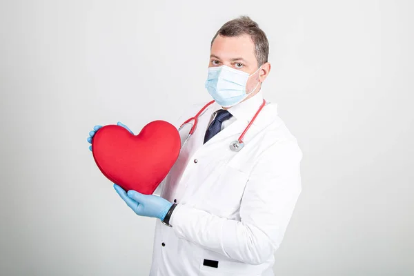 Beyaz cüppeli, maskeli, steteskoplu, kırmızı kalpli bir doktor.