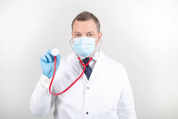 Steteskoplu beyaz cüppeli ve maskeli bir doktor. 
