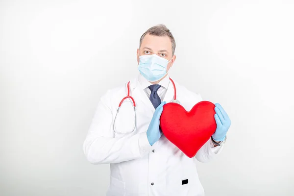 Beyaz cüppeli, maskeli, steteskoplu, oyuncak kırmızı kalpli bir doktor.