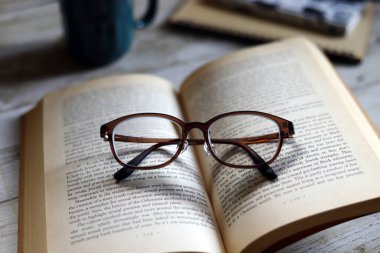 Karton kapaklı kitap ve gözlük, kahve içerken okumak, dinlenme zamanı.