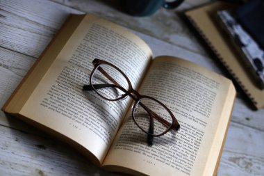 Karton kapaklı kitap ve gözlük, kahve içerken okumak, dinlenme zamanı.