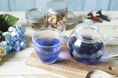 Bright blue color butterfly pea flower herb tea in a glass teapot and a cup